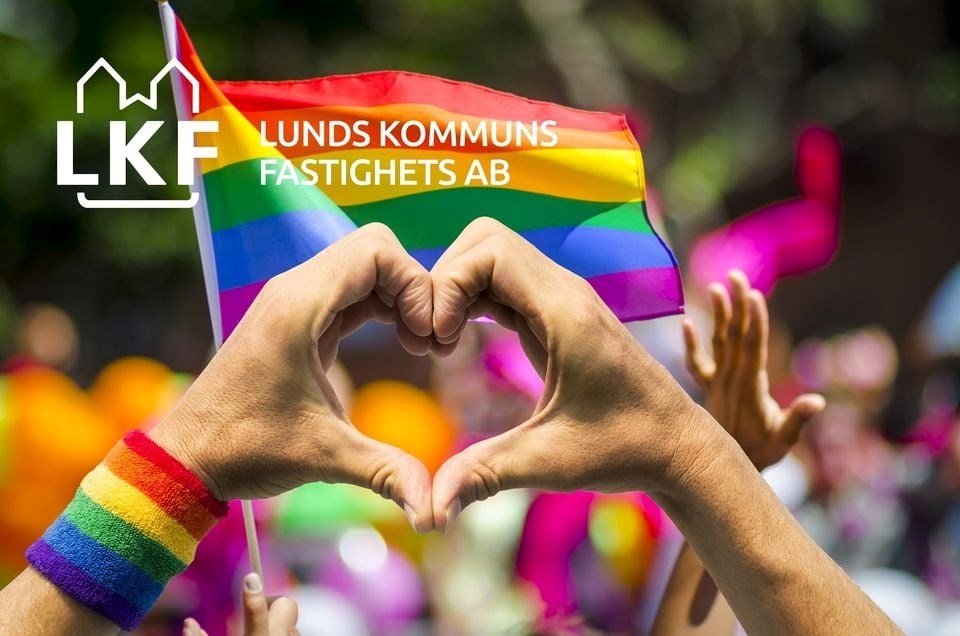 hand som formar hjärta framför en prideflagga